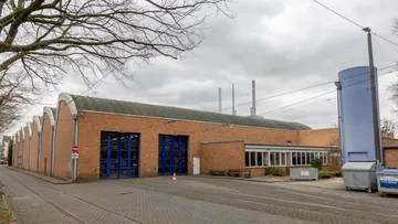 Wir sehen die Rückseite des Werkstattgebäudes auf dem Betriebshof Glocksee. Zwei blaue Tore sind geschlossen.