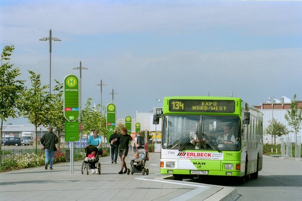 Ein MAN Bus mit Wagennummer 7764 steht an einer Haltestelle der Expo.