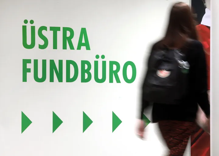 Eine Person geht ins Fundbüro der ÜSTRA. An der Wand weisen Pfeile den Weg. Darüber steht "ÜSTRA Fundbüro".