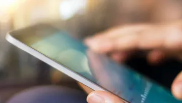 Nahaufnahme auf ein Handy, das jemand in der Hand hält. 