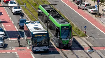 Luftaufnahme von einem Hybridbus und einem T W 3000 auf einer Kreuzung. Beide Fahrzeuge fahren in Richtung "Hannover ZOB". Der Bus fährt als Linie 500, die Bahn als Linie 17. Hinter und neben den Fahrzeugen fahren Autos und ein Fahrrad.