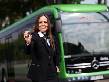 Eine ÜSTRA Mitarbeiterin steht vor einem Bus.