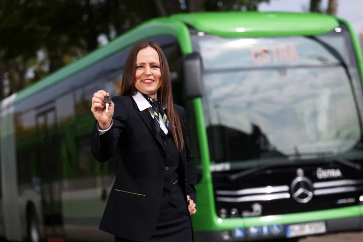 Eine ÜSTRA Mitarbeiterin steht vor einem Bus.