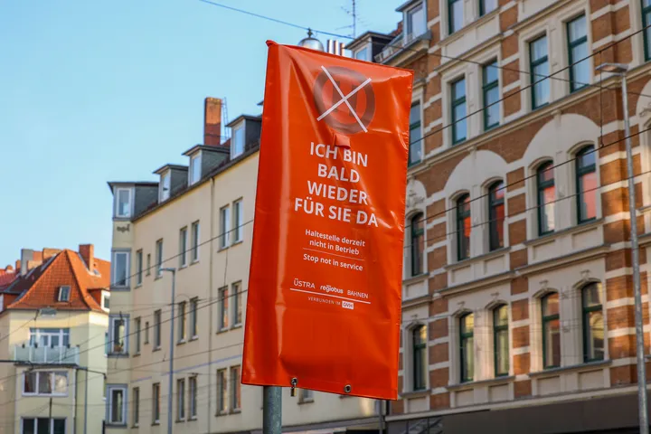 Ein Haltestellenmast mit orangem Überzug. Darauf steht: "Ich bin bald wieder für Sie da"