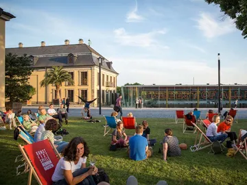 Besuchende sitzen auf einer Wiese in den Herrenhäuser Gärten.