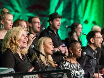 Frauen und Männer singen in einem Chor.
