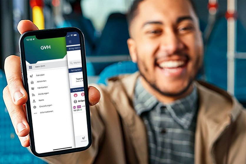 Ein junger Mann sitzt in einem regiobus Fahrzeug und zeigt sein Handy, welches die GVH App zeigt.