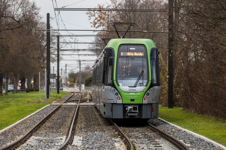Eine Stadtbahn der Linie 2 mit dem Fahrtziel "Alte Heide" steht auf Gleisen umrahmt von Bäumen.