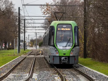 Eine Stadtbahn der Linie 2 mit dem Fahrtziel "Alte Heide" steht auf Gleisen umrahmt von Bäumen.