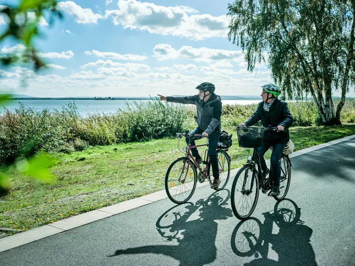 Zwei Fahrradfahrer fahren auf einem Radweg entlang des Steihuder Meers.