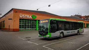 Im Vordergrund steht ein Marcedes Citaro Bus. Im Zielanzeiger steht die Linie 300 in Richtung Pattensen ZOB. Der Bus steht auf dem Parkplatz des Betriebshofes Vahrenwald. Im Hintergrund sieht man die Fahrzeughalle mit dem ÜSTRA Logo.