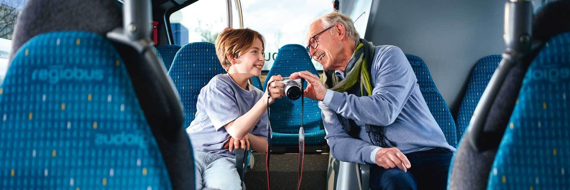 Coverbild des GVH journals 02.2023: Ein Großvater und sein Enkel sitzen in einem Bus und schauen sich gemeinsam Fotos auf einem Kameradisplay an.